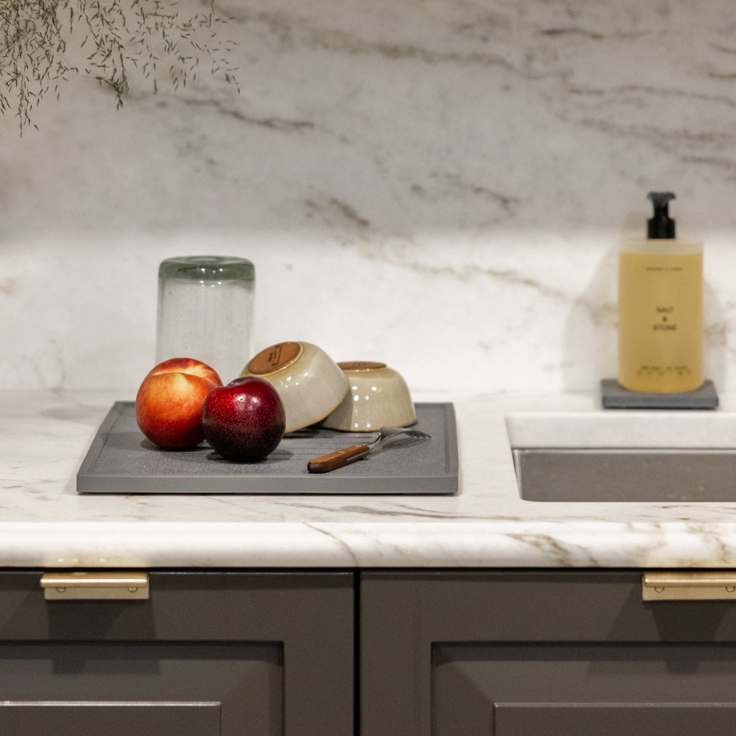 Kitchen counter with apples, bowls, drying on dish mat and marble backsplash