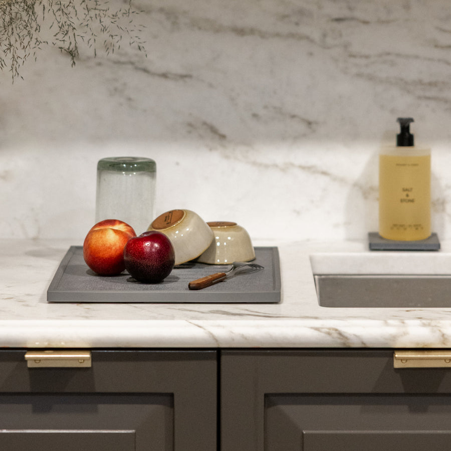 Kitchen counter with apples, bowls, drying on dish mat and marble backsplash