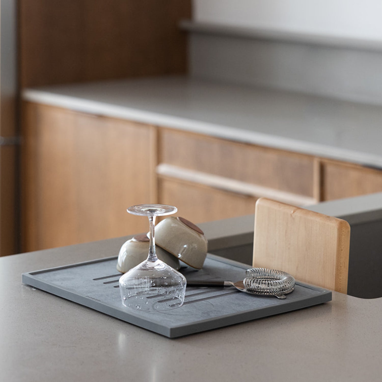 grey dish drying pad with bar utensils and glasses