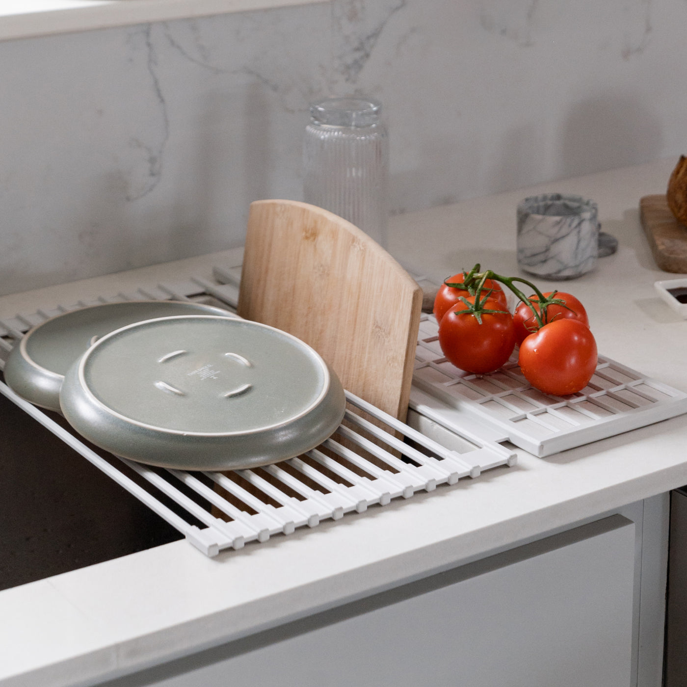 Dish pad rolled over a kitchen sink with dishes and fruit drying on it