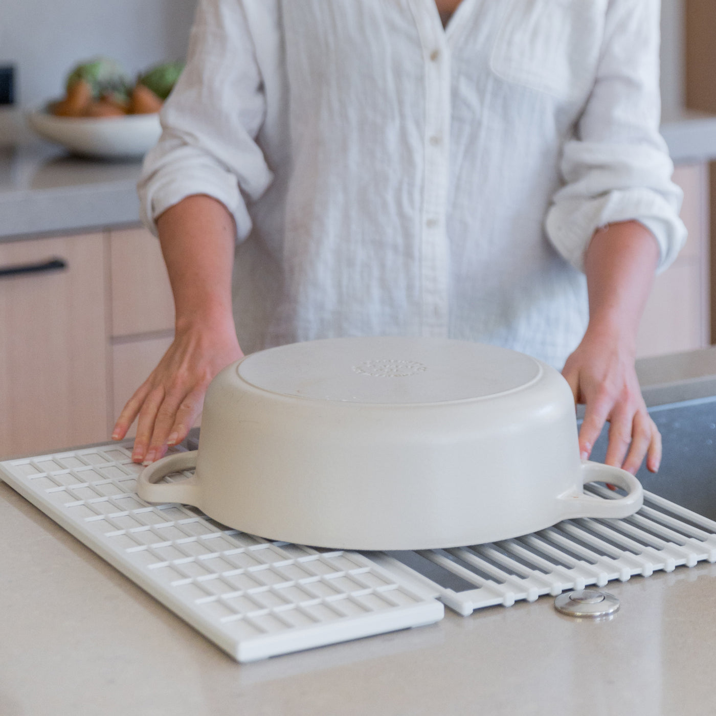 person placing a large, heavy pot onto an over the sink dish pad