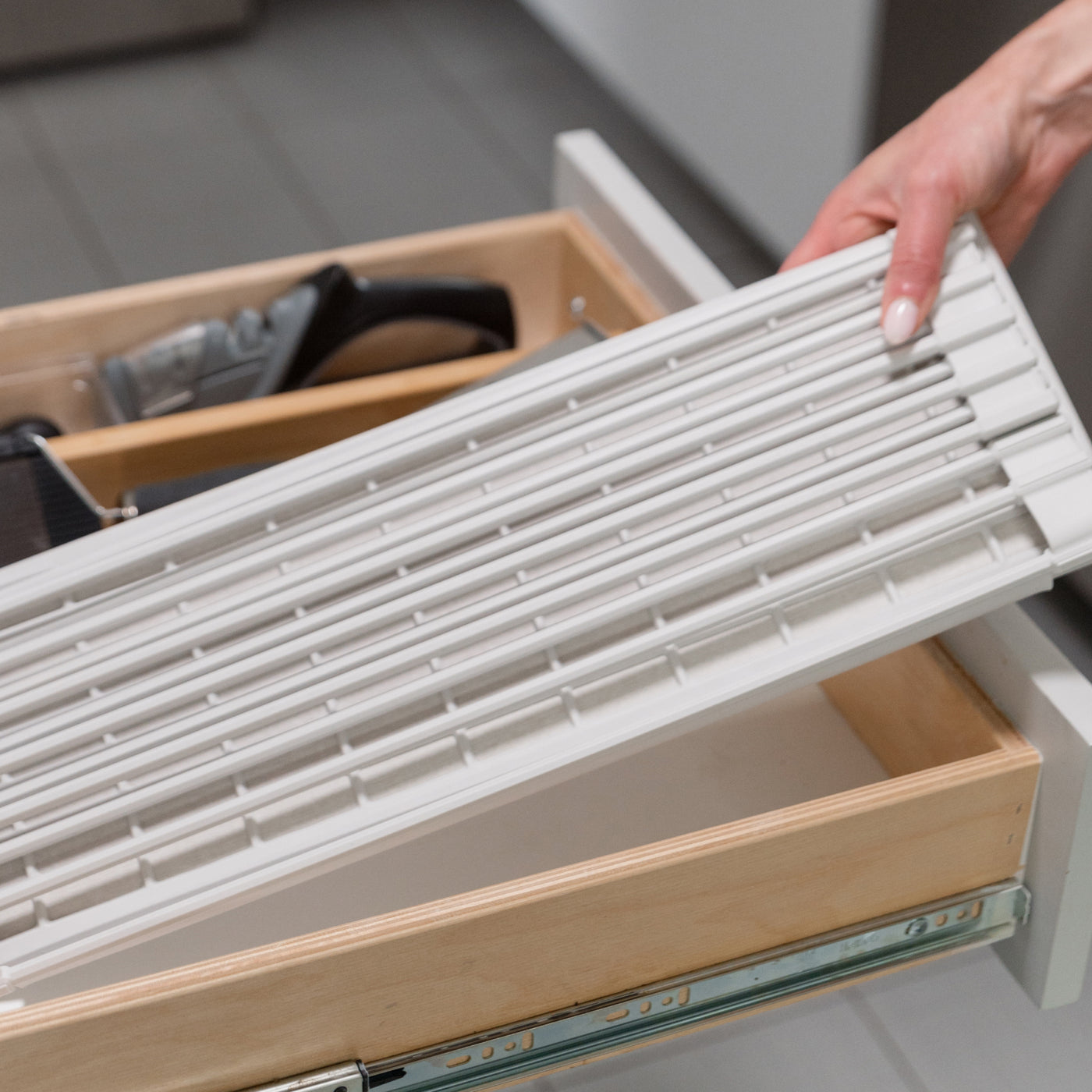 person placing a folded dish pad into a kitchen drawer