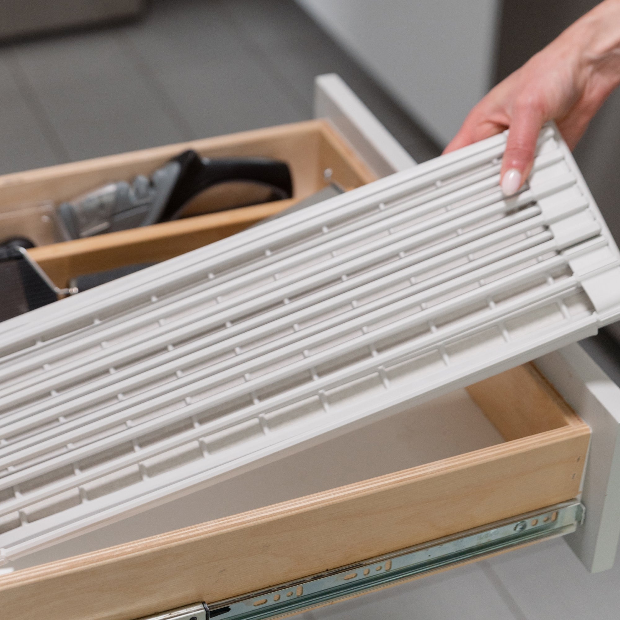 person placing a folded dish pad into a kitchen drawer