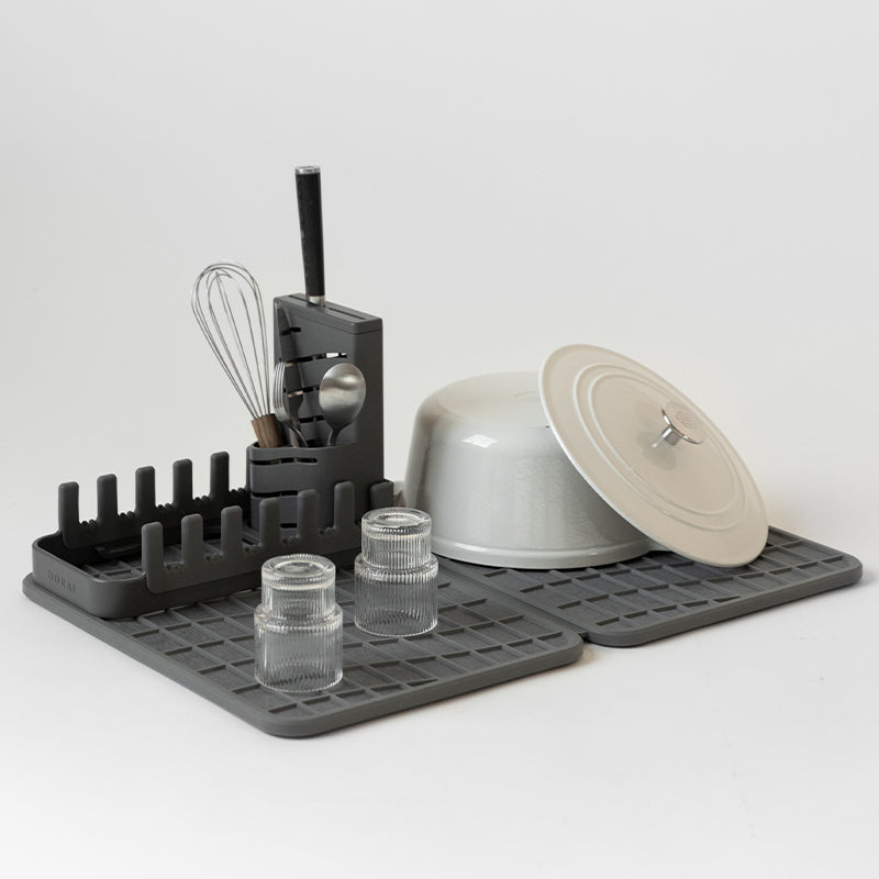 cast iron pot and glasses drying on dark grey dish mat with dish rack 