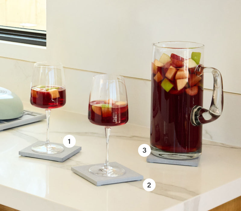 Wine glasses + Large Pitcher on large coasters numbered 1-3 with sangria and fresh fruit. 