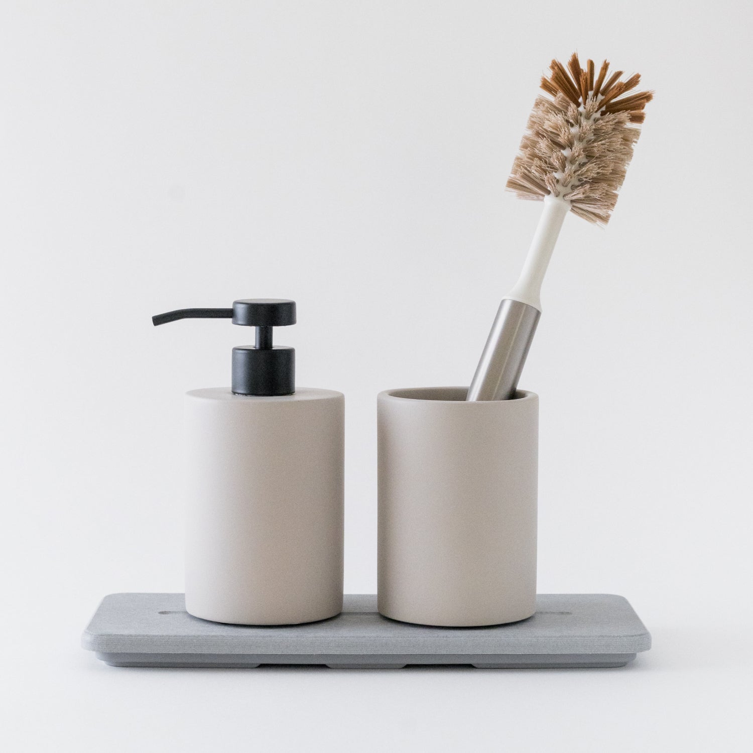 Bathroom accessory set with soap dispenser, toothbrush holder, and brush on a white background