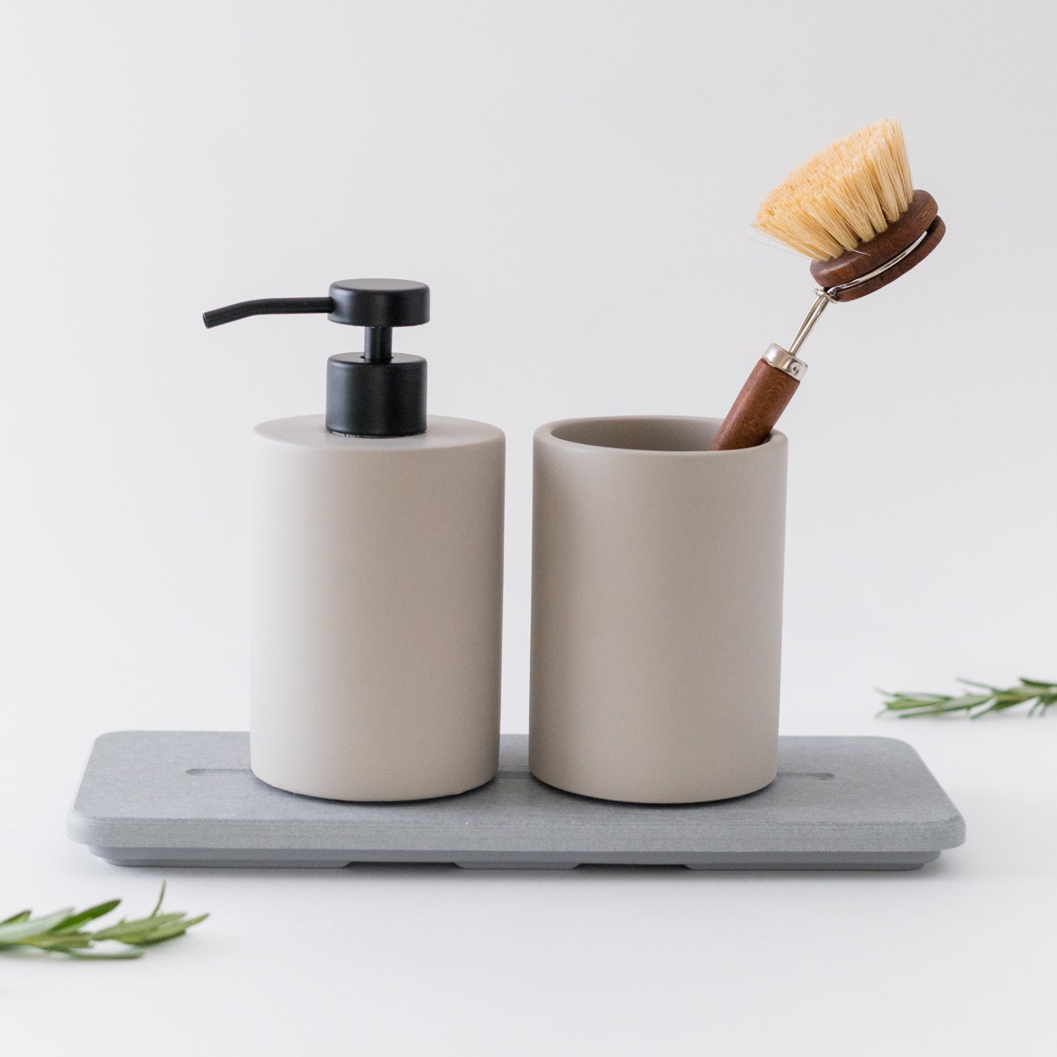 Bathroom set with beige dispenser, cup, and brush on a gray tray.
