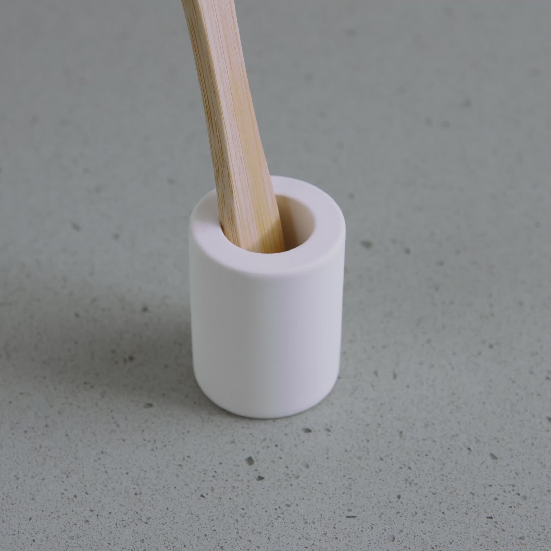 Placing a wet toothbrush into quick-drying , small Soft Beige toothbrush holder. 