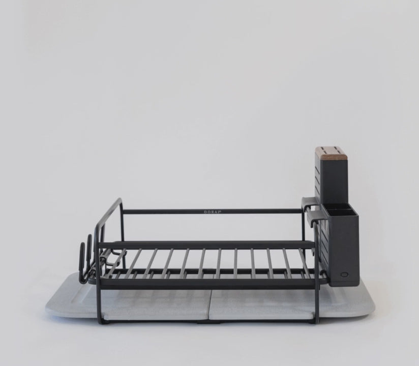 Dish rack with plates, bowls, pots, cutting board, glasses, and utensils. 