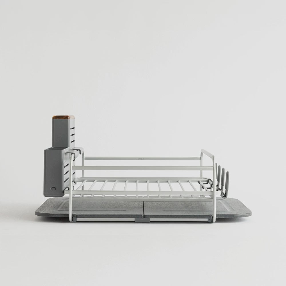 grey and silver dish drying rack being filled with dishes