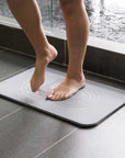 woman stepping out of shower onto slate zen bath stone mat