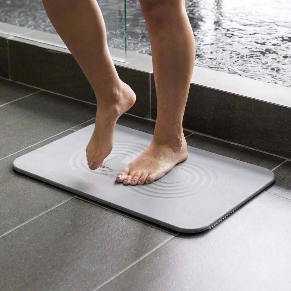 woman stepping out of shower onto slate zen bath stone mat