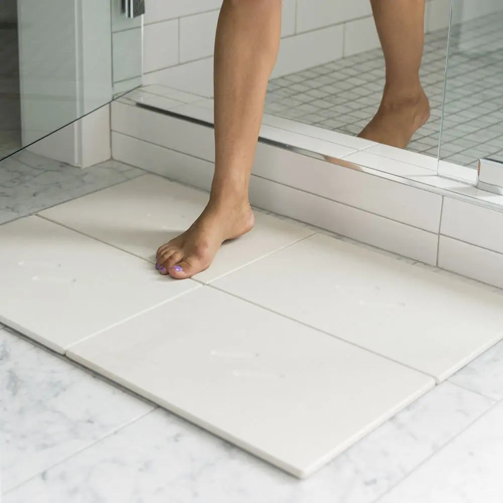 Woman stepping out of shower onto large bath stone mat sandstone 