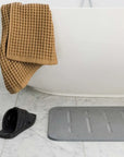 Bath Stone Mat Rain Slate next to bath tub and shoes and towel