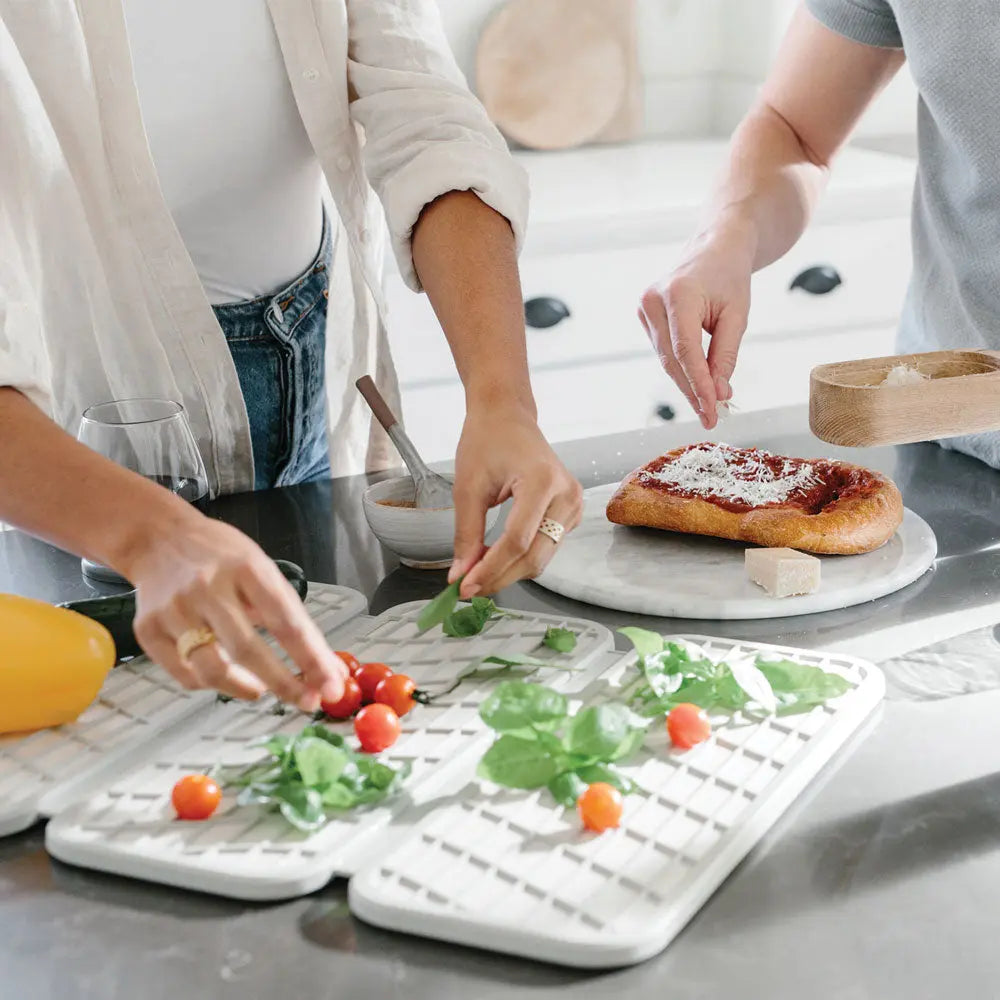 Dorai Dish Pad with vegetables and people prepping pizza