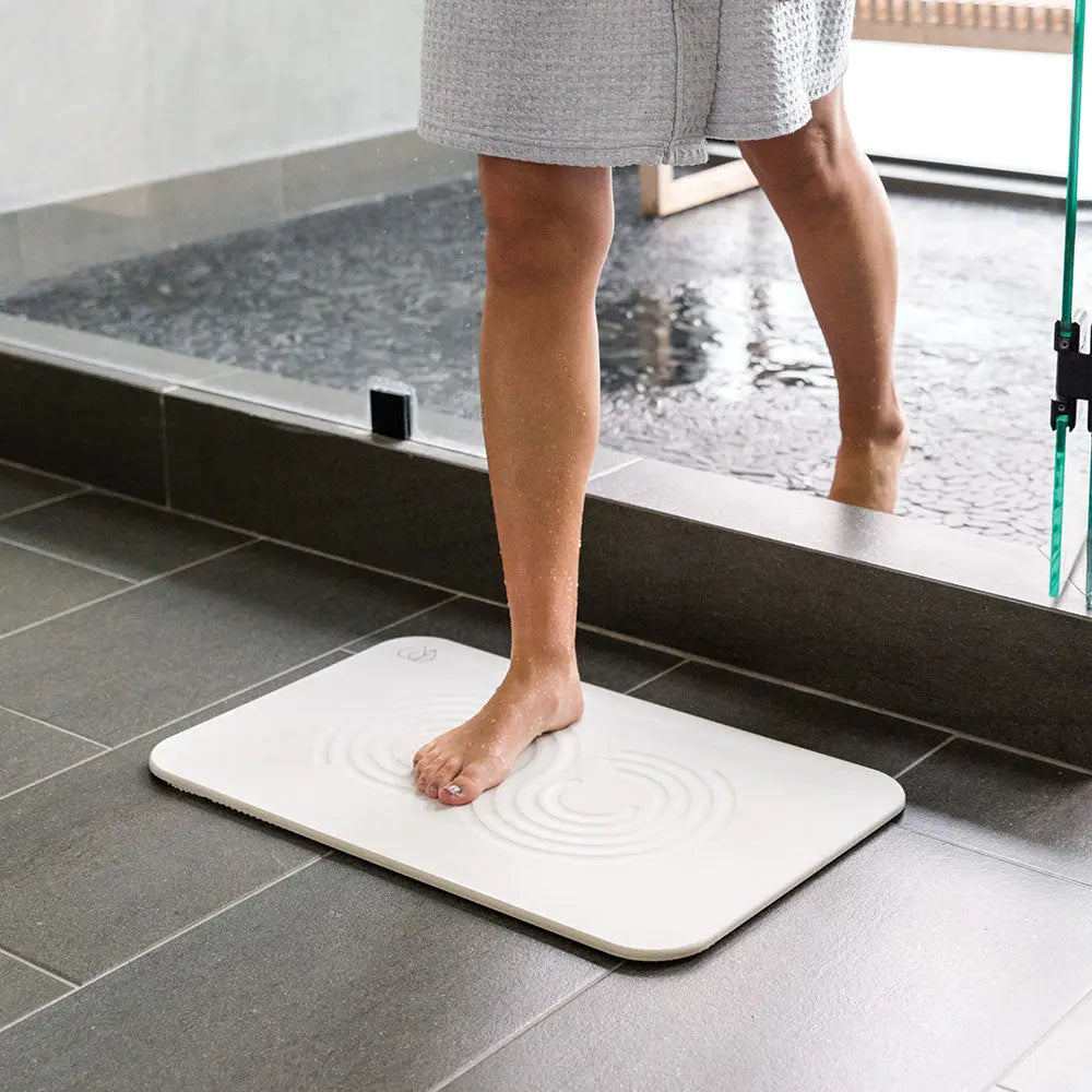 Woman stepping out of shower onto Bath Stone™