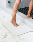 Woman stepping into shower from Sandstone Bath Stone™